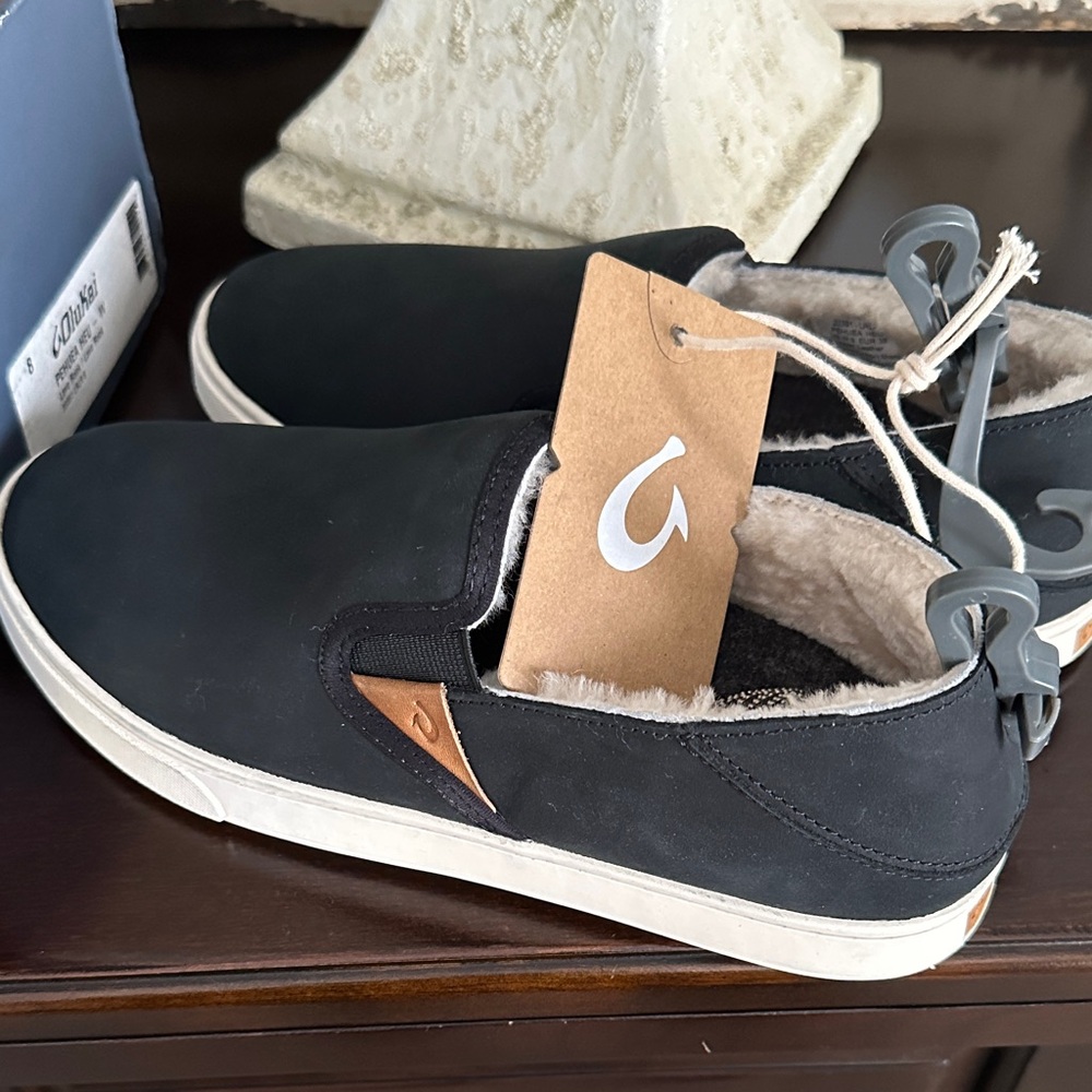 OluKai Women’s black leather upper slip on sheep fleece lined shoes